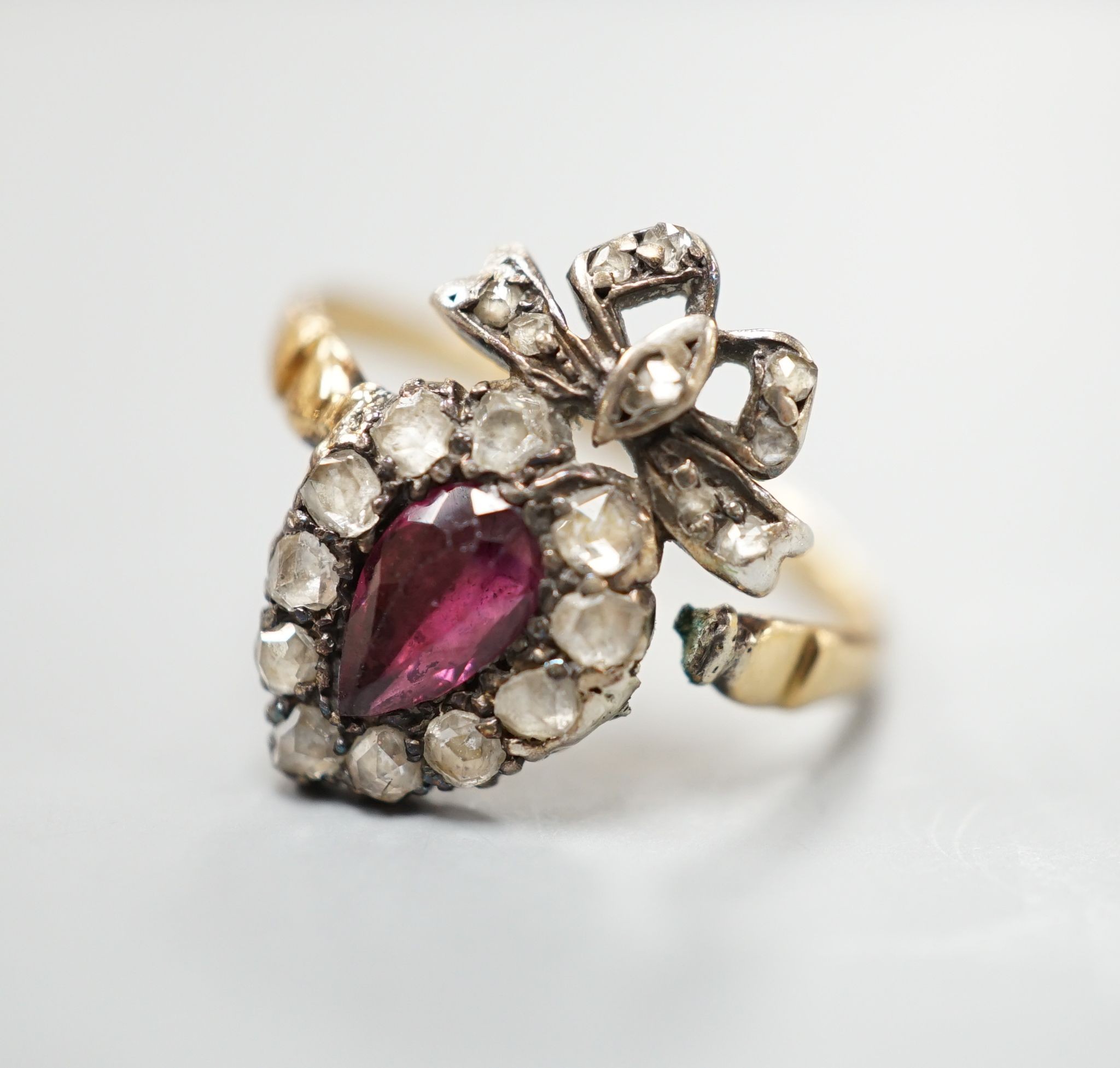 A 19th century yellow metal, garnet and rose cut diamond set heart shaped ring, with ribbon bow crest (shank broken), approx. size H, gross weight 2.2 grams.
